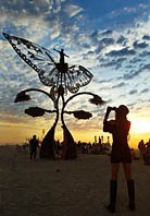 Woman taking a picture of metal butterfly wings art sculpture