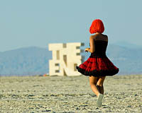Burning Man Girl dancing next to the End sign