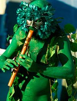 Green painted man playing his flute