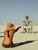 Woman pointing finger at human sized metal skeleton sculpture
