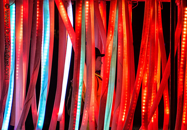 Woman walking between illuminated color tubes