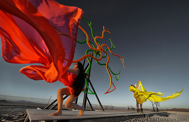 Dancing girls in front of the spinning wheels by PDA. Windmills art installation. 