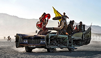 Girls dancing the on hood of an Art Car from Department of Mutant vehicle.