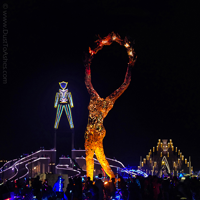 Installation of the headless woman rising hands to release the butterflies called Release by Dana Albany. Her art sculpture is aligned with the Burning Man as if she was dancing with him.