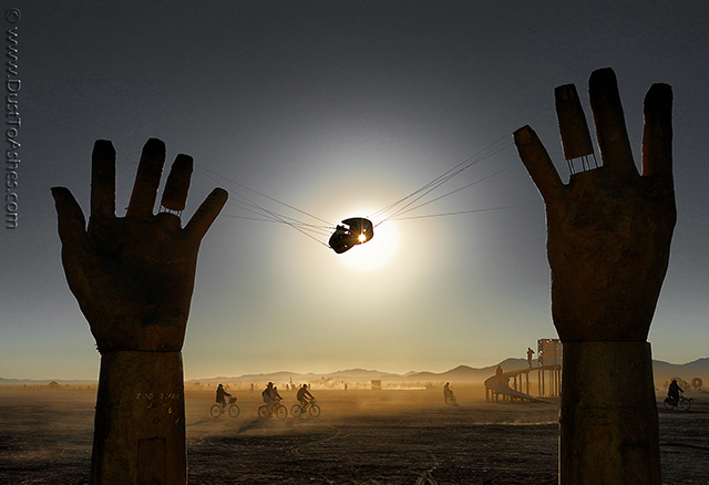 Silhouettes of two hands art sculpture rising out of the desert. 